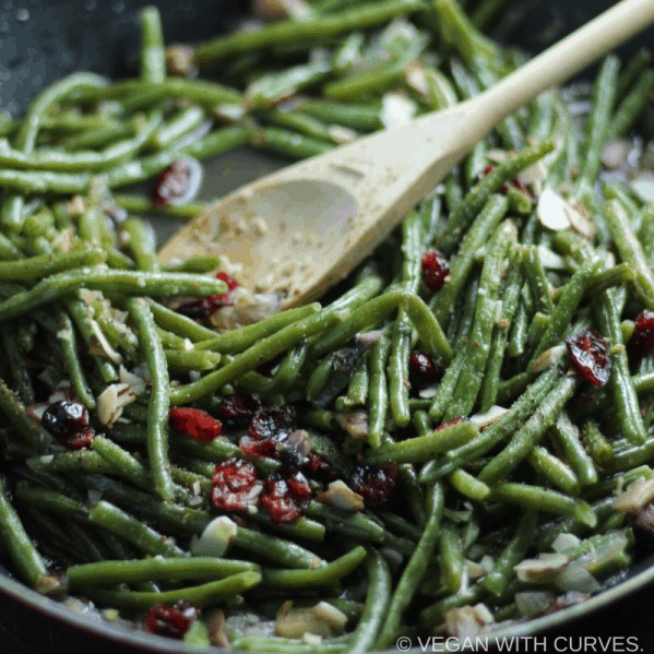 green beans in a pan with wooden spoon
