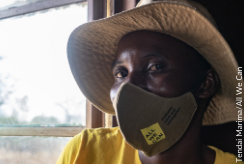 A woman in a beige hat, yellow top and facemask stares into the camera. In the background is an open window, with sunlight streaming in. Image: Tendai
Marima/All We Can
