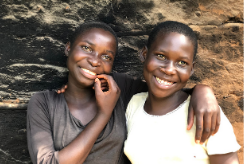 Twins sisters stand outside their home in Uganda