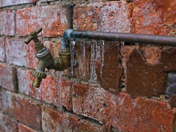 Frozen pipe and faucet leaking on brick wall