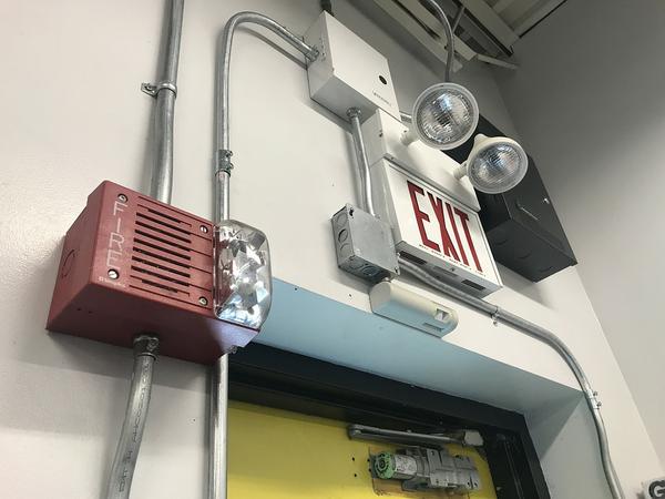 Fire alarm and exit sign above door