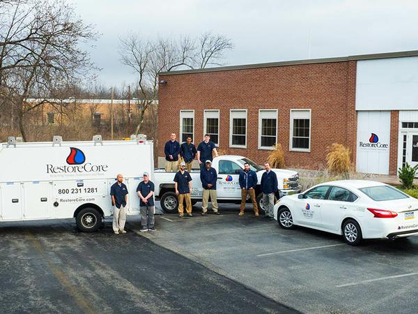 RestoreCore employee group photo with company trucks.