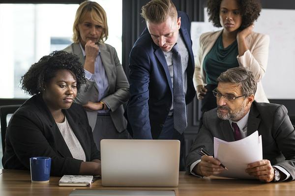 businesspeople gathered around laptop while creating a disaster plan