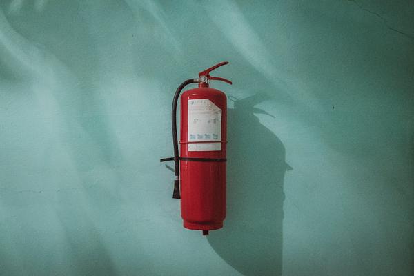 red fire extinguisher on a blue wall