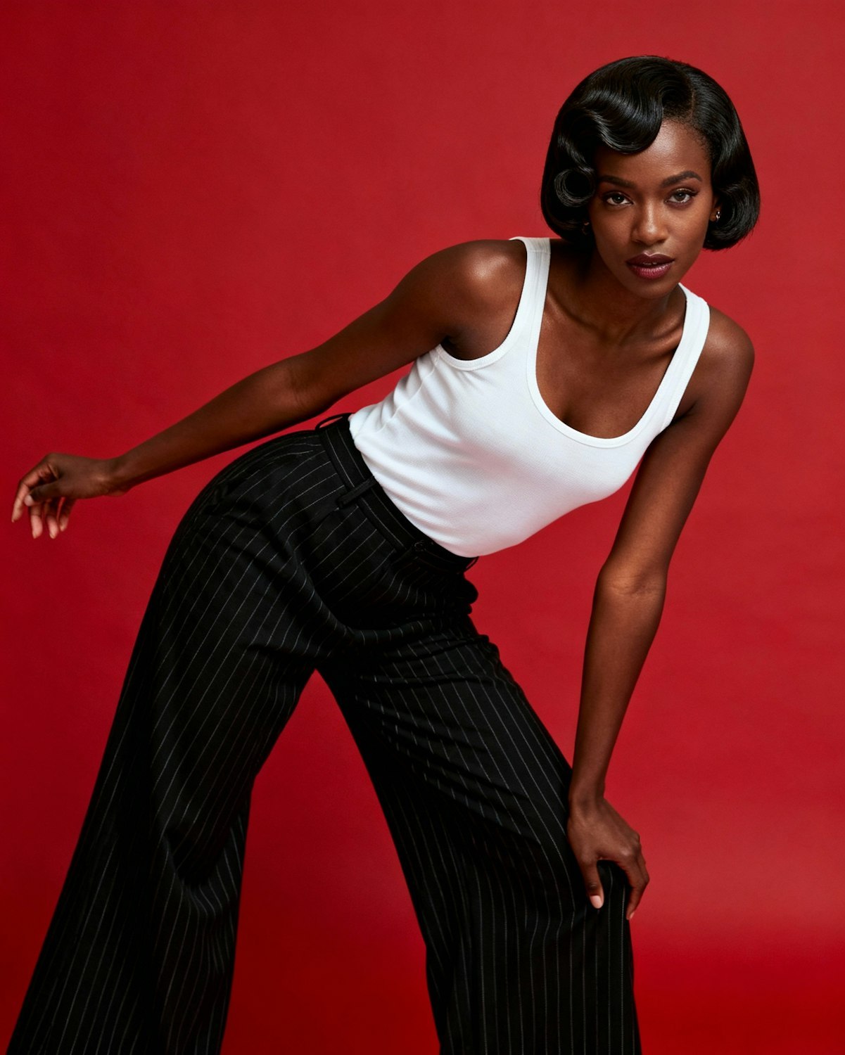 A confident woman of color standing tall against a bold red backdrop