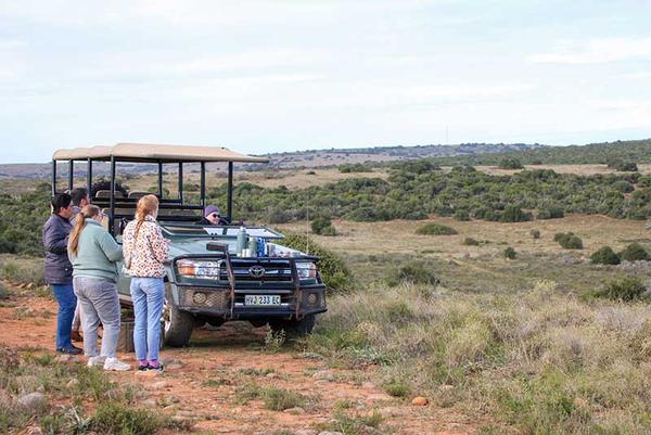 Group of people standing next to safari vehicle