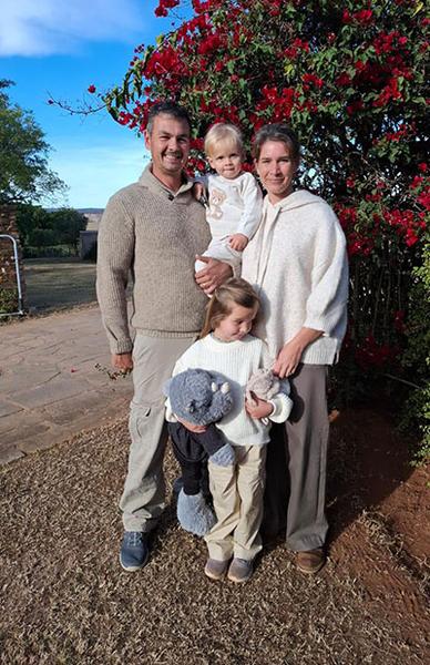 Family posing in front of flowering bush