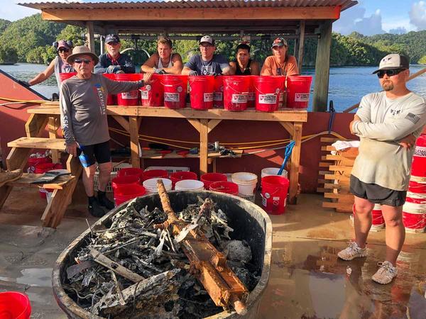  "Palau MIA recovery mission. The screening station team takes a short break to show the tasks at hand of examining all the material and debris coming up from
aircraft site that is 120 feet deep.": Harry Parker