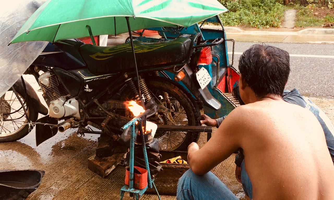 Men fix motorcycles in the rain