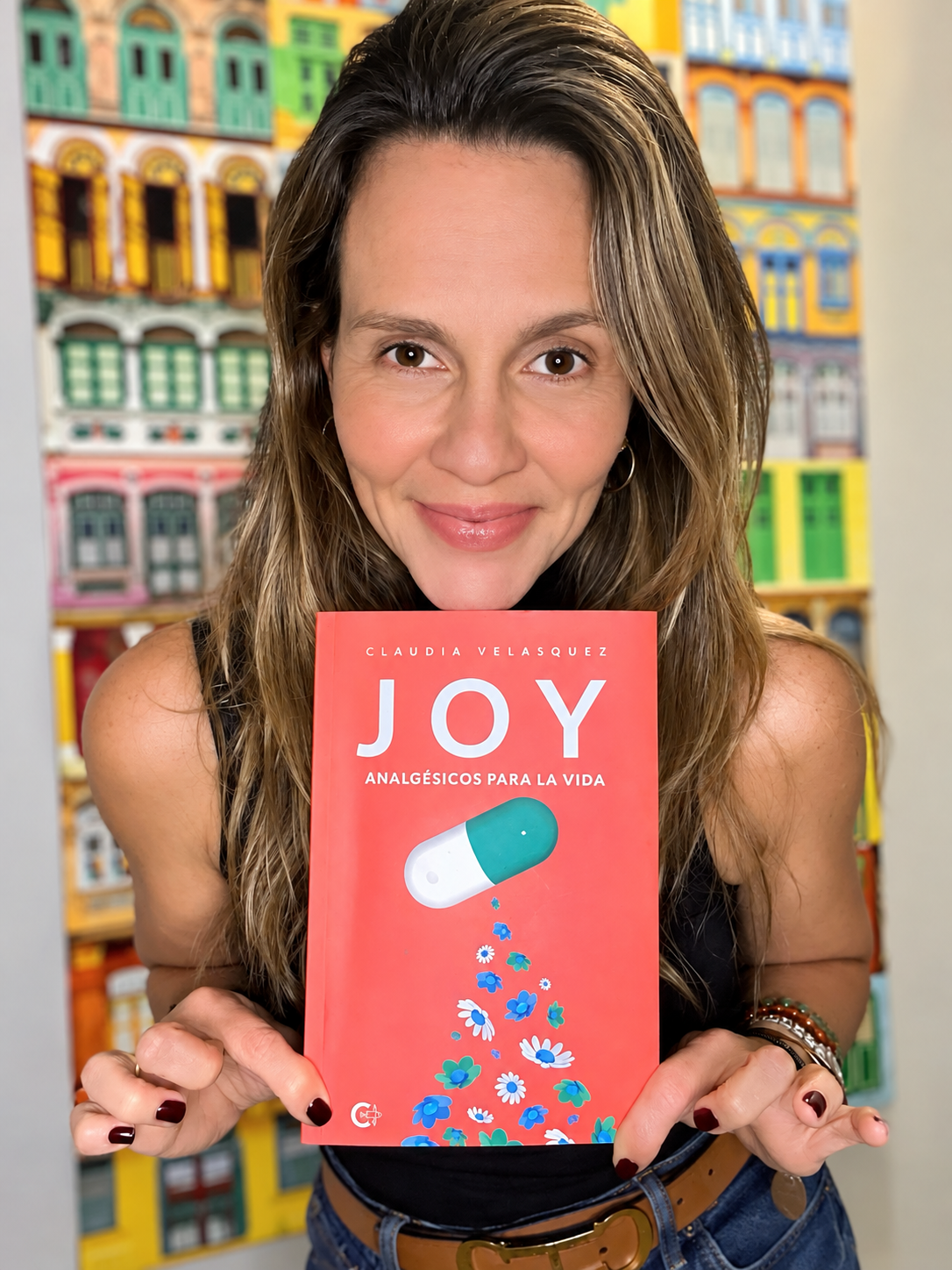 Claudia Velásquez sosteniendo su libro Joy: Analgésicos para la vida
