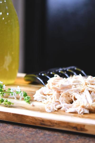 Shredded chicken on an olive cutting board