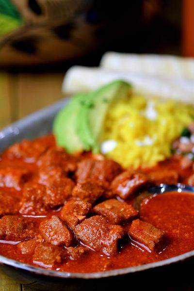 closeup of chile colorado with avocado and rice
