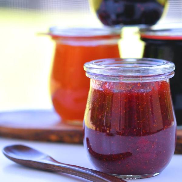 glass jar of strawberry jam on a picnic table