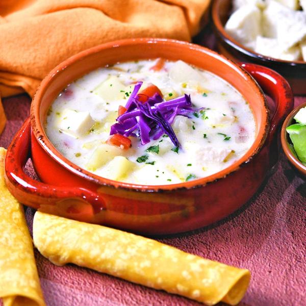 Mexican cheese and potato soup in red pottery bowl