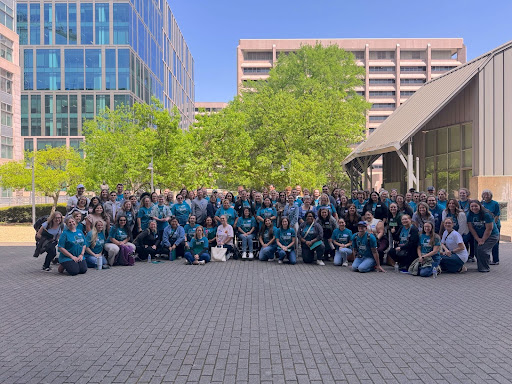 A large group of self-advocates in blue shirts gather outside government buildings and smile for the camera at Autism Society of Texas’ Texas Autism Advocacy Day.