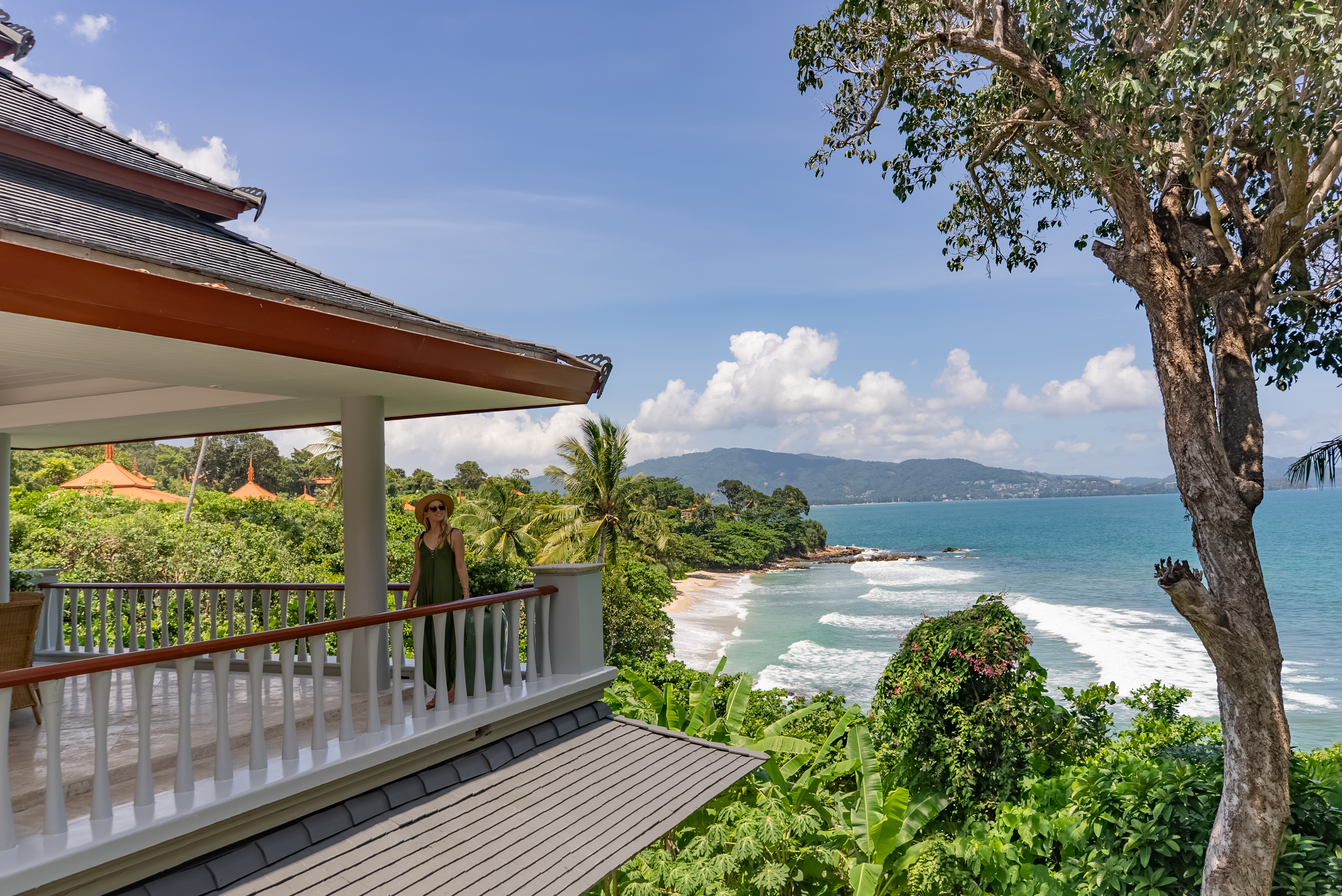 Woman on a Thai-style villa terrace overlooking a tropical bay and turquoise sea in Phuket