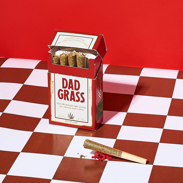 Custom pre-rolled CBD joints from our friends at Dad Grass rolled up in cute little bottles on a blue tablecloth