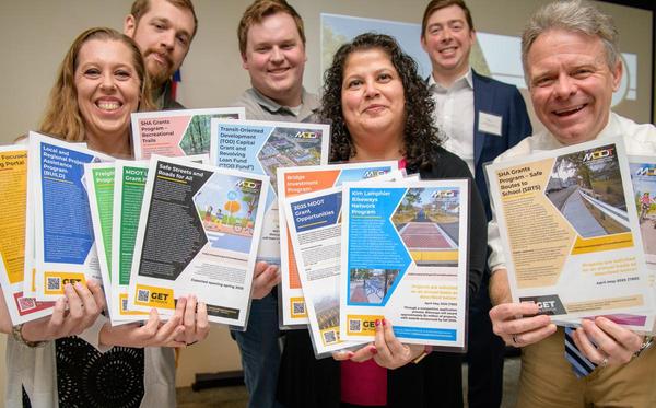 group of smiling people holding colorful fliers