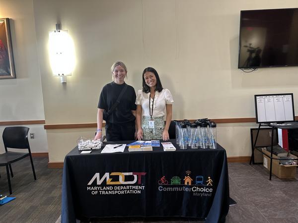 photo of two smiling girls standing behind ccm outreach table
