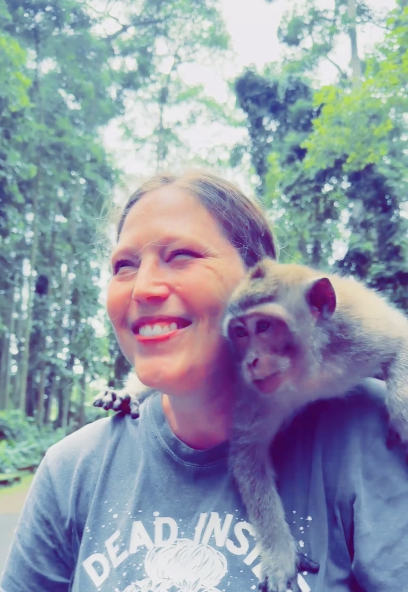 A joyful woman with a monkey on her shoulder in a lush jungle