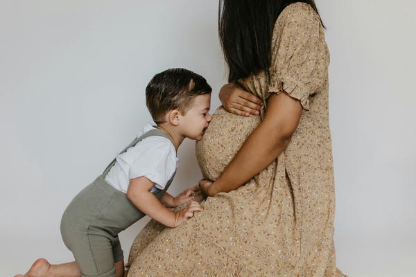 Little boy kissing his pregnant momma's belly