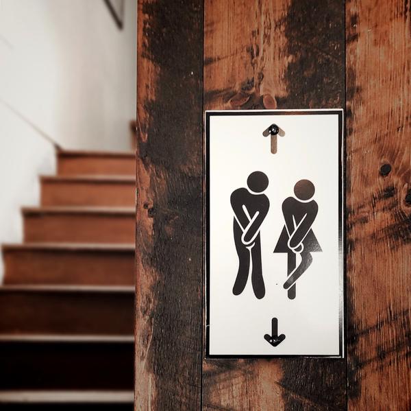 Bathroom sign of man and woman crossing their legs