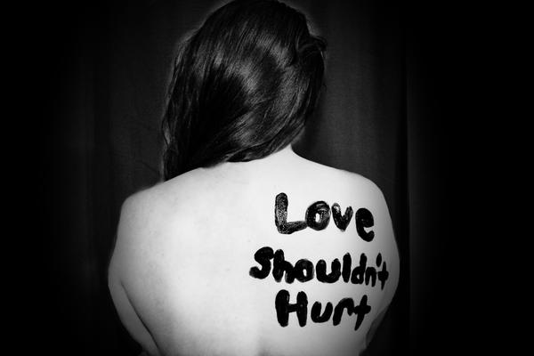 Woman with the words "Love Shouldn't Hurt" written on her naked back
