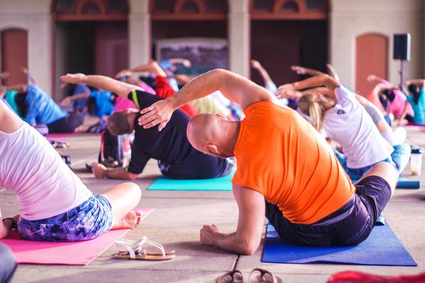 Women and men sitting on yoga mats in an exercise class