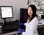 UC pharmacy PhD grad Tianyi Liu stands in front of a computer monitor in a biomedical laboratory.