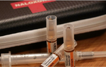 Three tubes of naloxone and a syringe lie in front of a Naloxone carry kit.