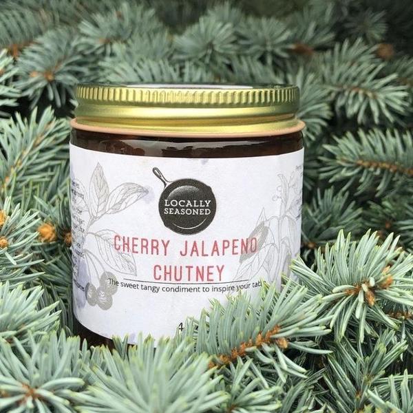 Image of a cherry jalapeno flavored chutney from Locally Seasoned resting in a pine tree.