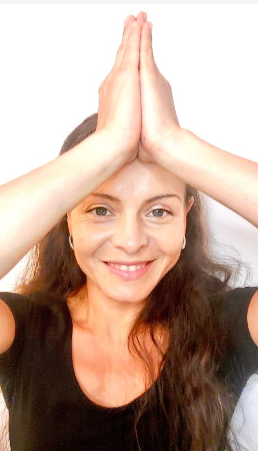 Constanza Rendon smiling with hands pressed together above her head in a calm prayer pose