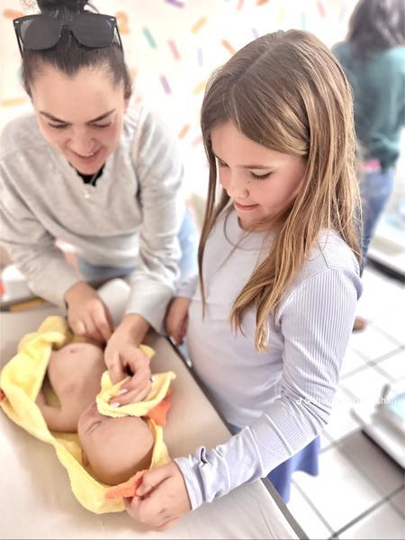 A mother and daughter wrapping a baby doll in a yellow duck towel