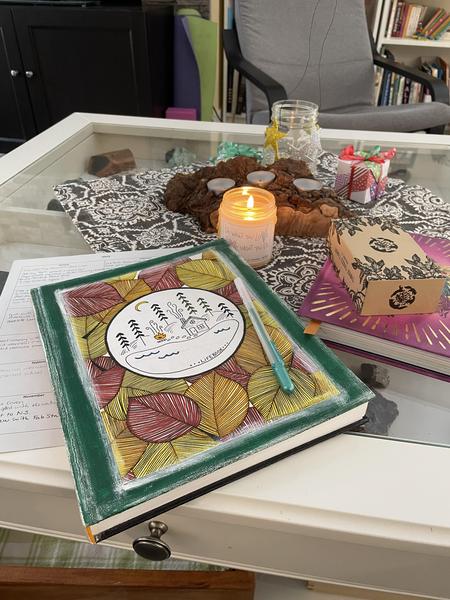 Reflection notebook, tarot deck, and candles on a table