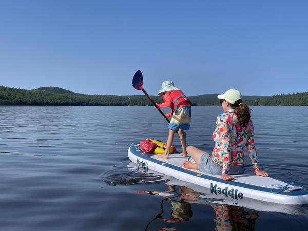 Stephanie's daughter paddling while Stephanie rides along on a calm lake
