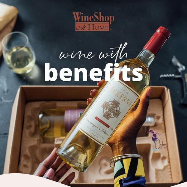 Hand holding a bottle of wine with the words Wine with Benefits