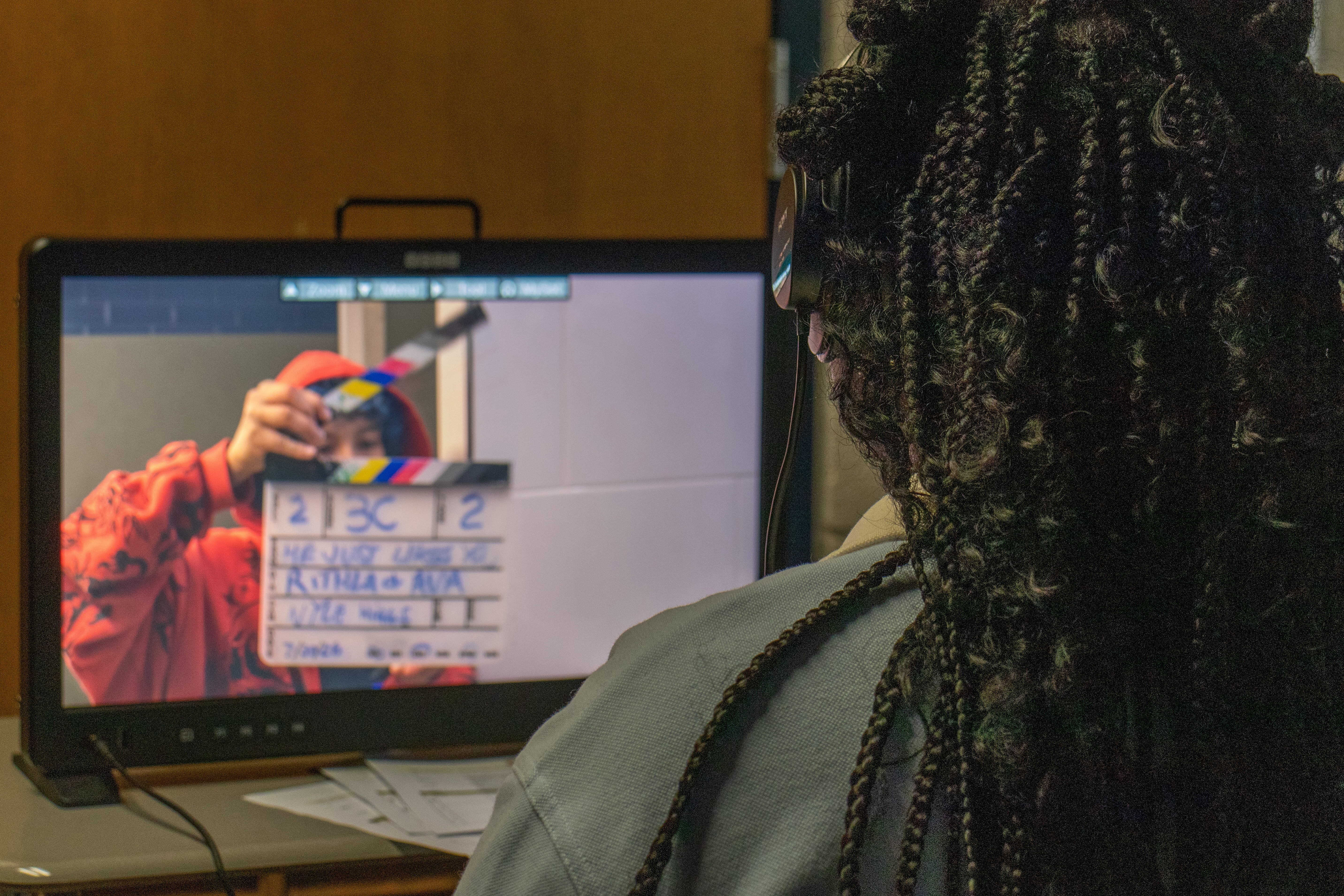 A student watches a take on the monitor as the slate marks the shot