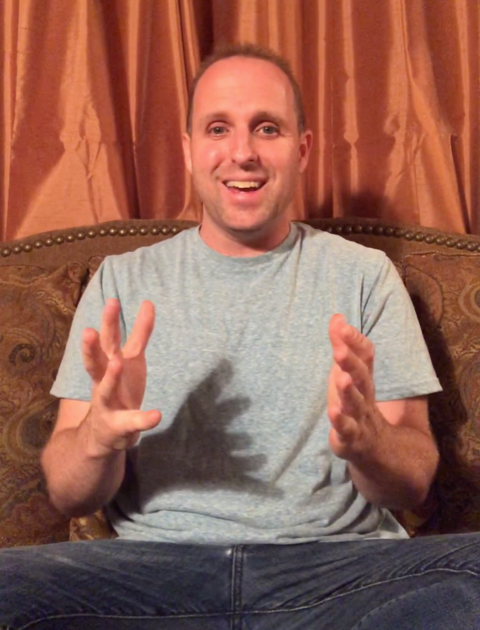 Brian Hogan speaking expressively, hands raised, seated on a sofa