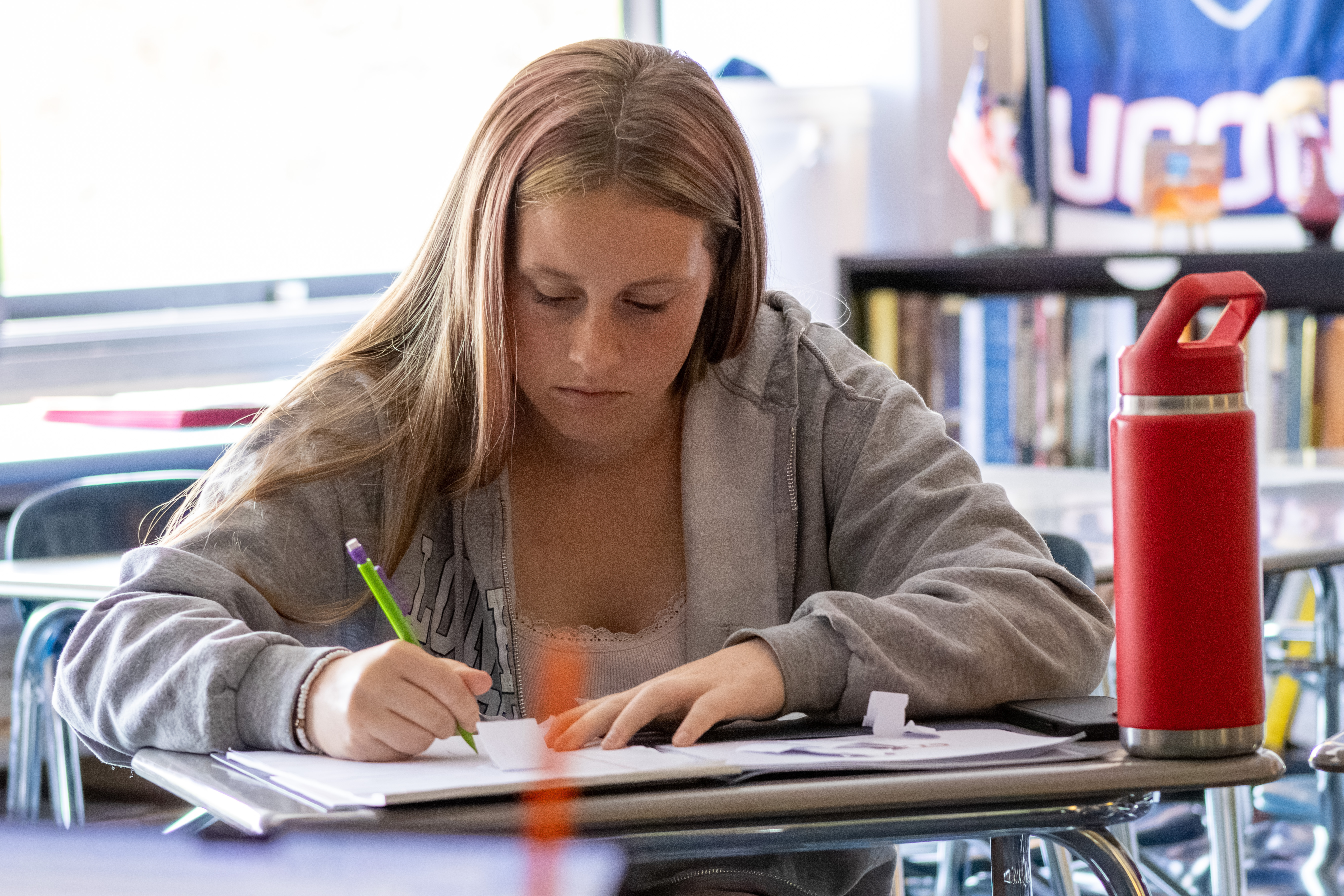 A high-school student writing at her desk in class