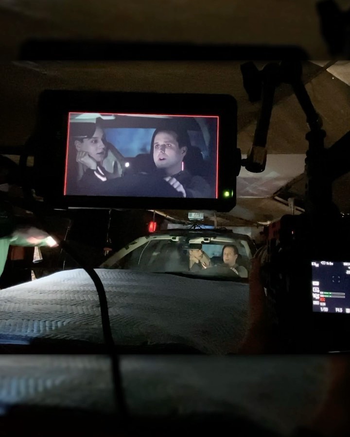 A director's monitor showing two actors performing a night driving scene in a car