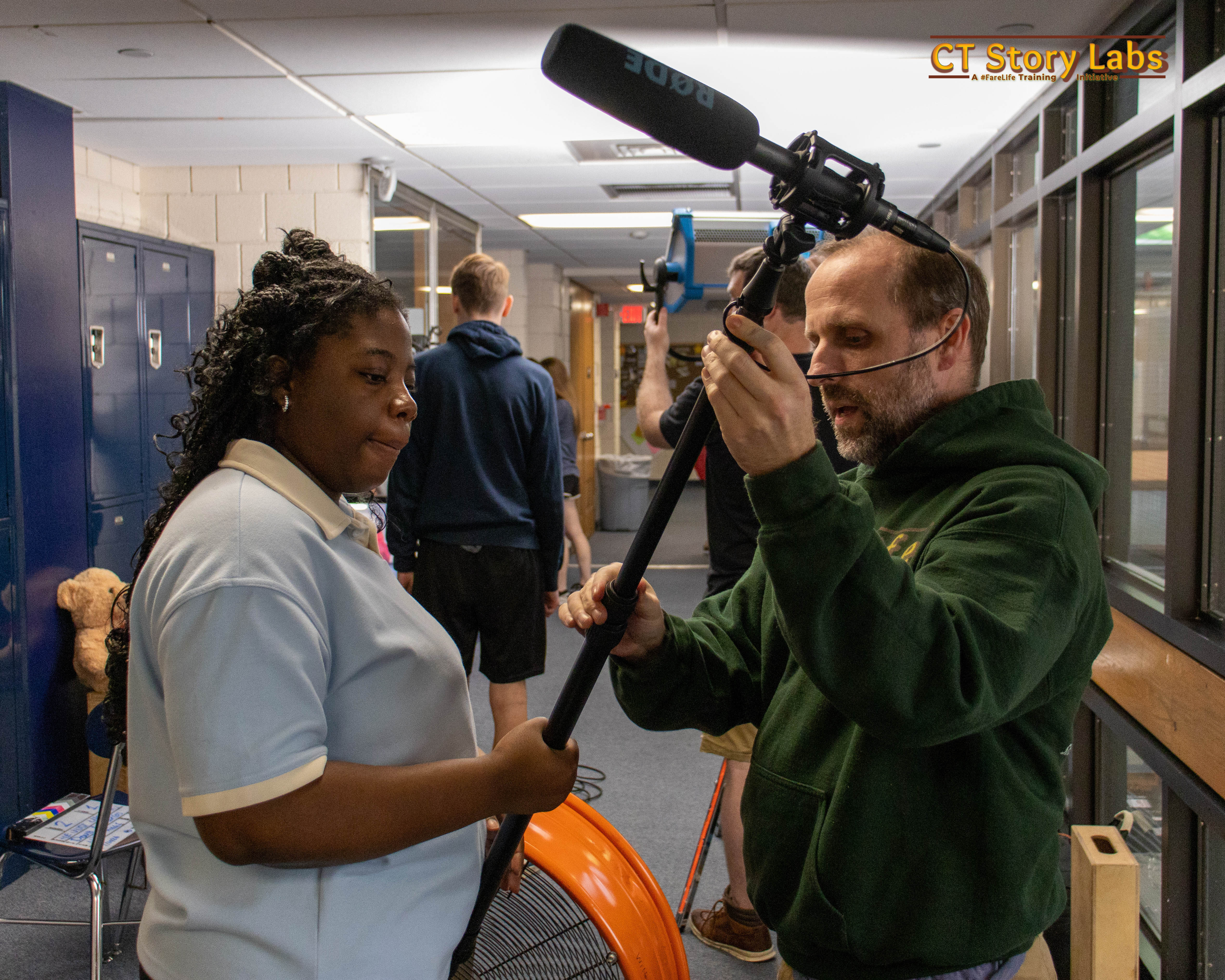 A student learning to hold a boom microphone on set