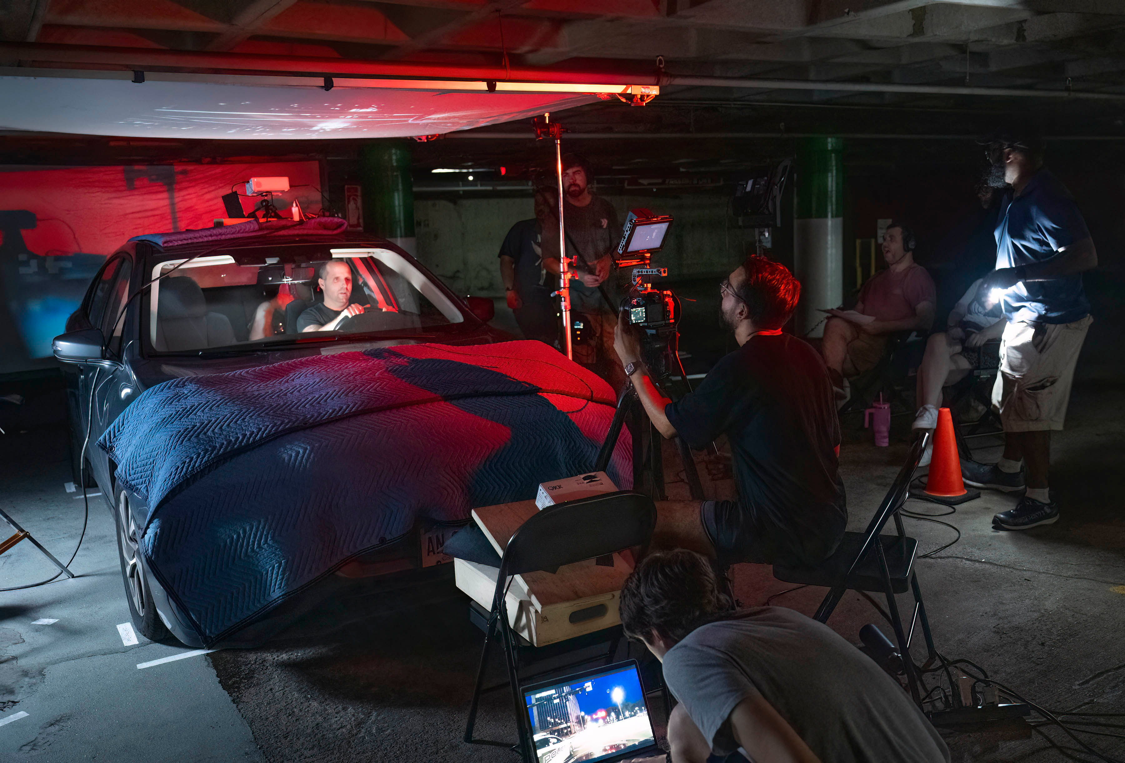 A #FareLife crew filming a red-lit night driving scene in a parking garage