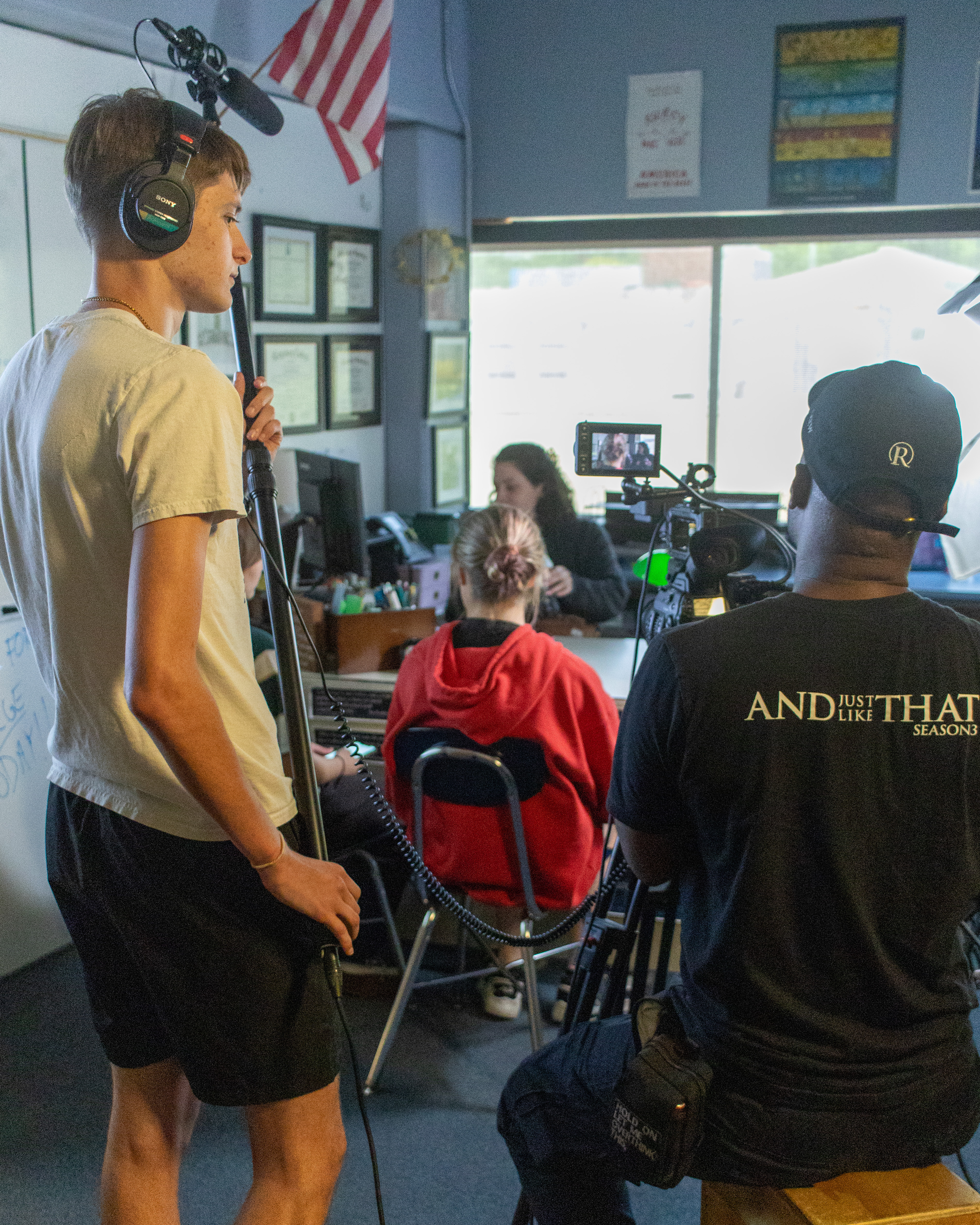 A student booms a scene while the camera operator frames the shot on set