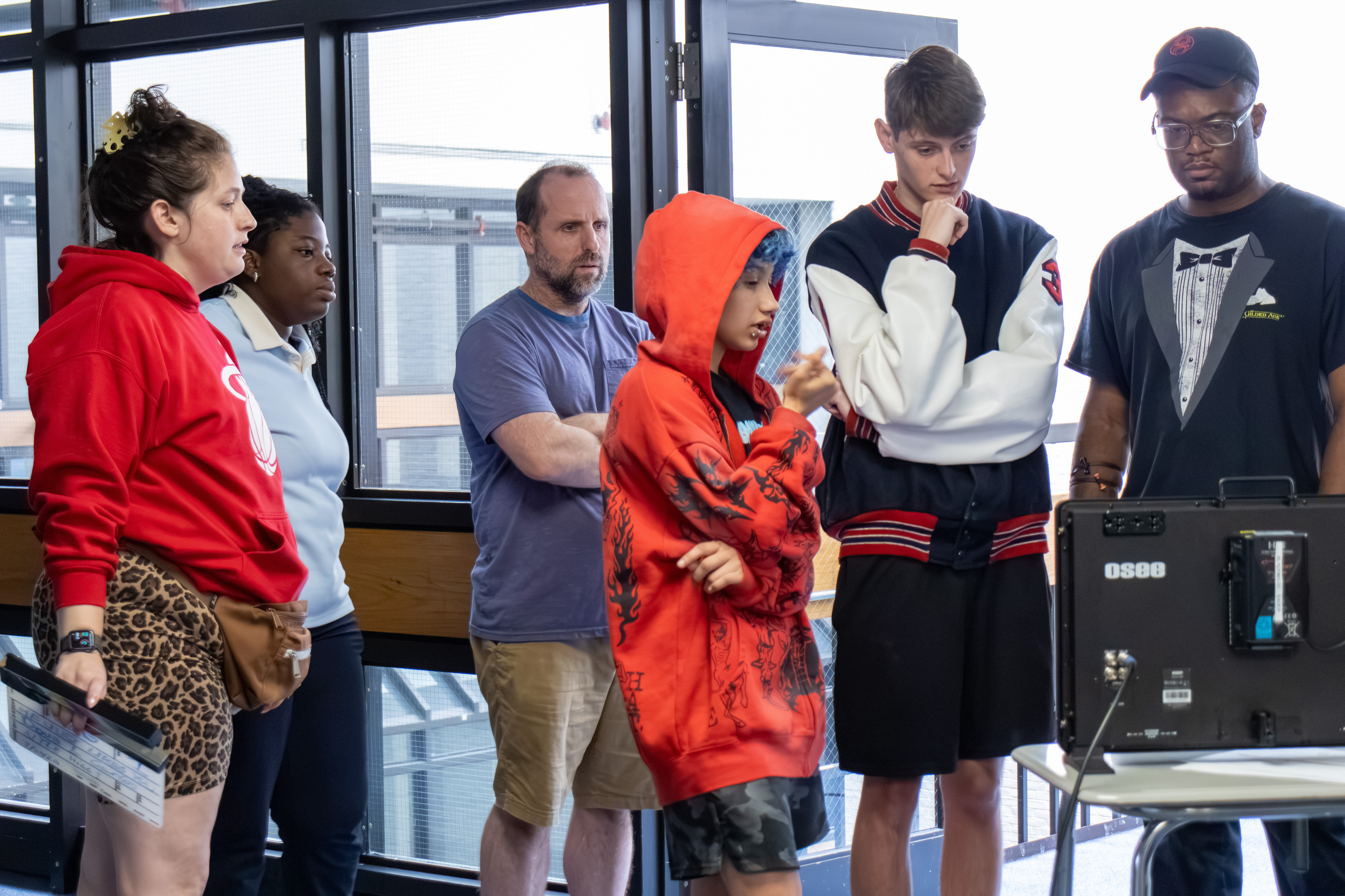 The student crew gathers around the monitor to watch a take play back