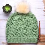 flat lay of lacy green crochet hat with faux pompom