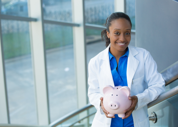 female doctor holding a piggy bank and smiling 