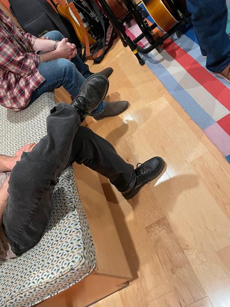 The legs of two people sitting on a bench.