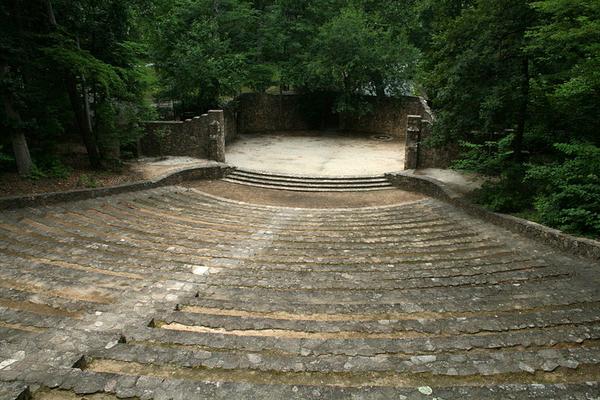 Photo of an empty stone amphitheater, taken from the top of the seating area toward the stage