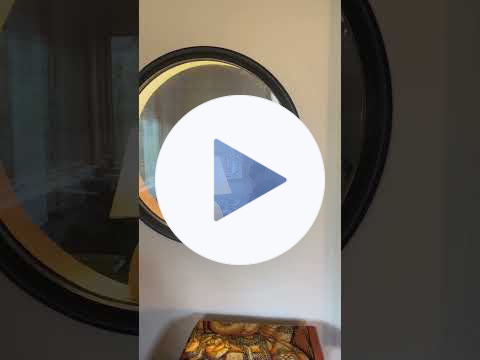 Video that pans from a computer screen showing musical tracks being recorded in a DAW to a drummer, scene through a window, not drumming during a quiet part of the song, then a pan back to the computer screen just as the drums kick back in. 
