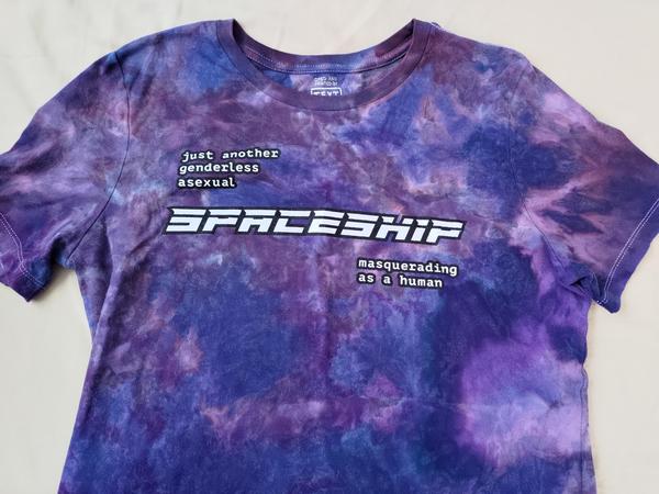 A purple tie-dyed shirt reading: just another genderless asexual spaceship masquerading as a human
